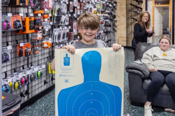 A boy holding up a blue target in front of his face.