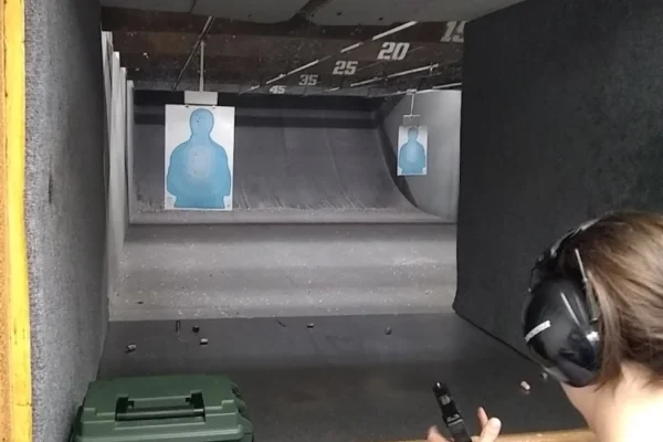 A person is shooting at a target in an indoor gun range.